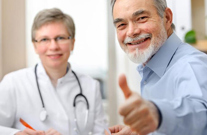 a patient giving thumbs up with doctor in the background