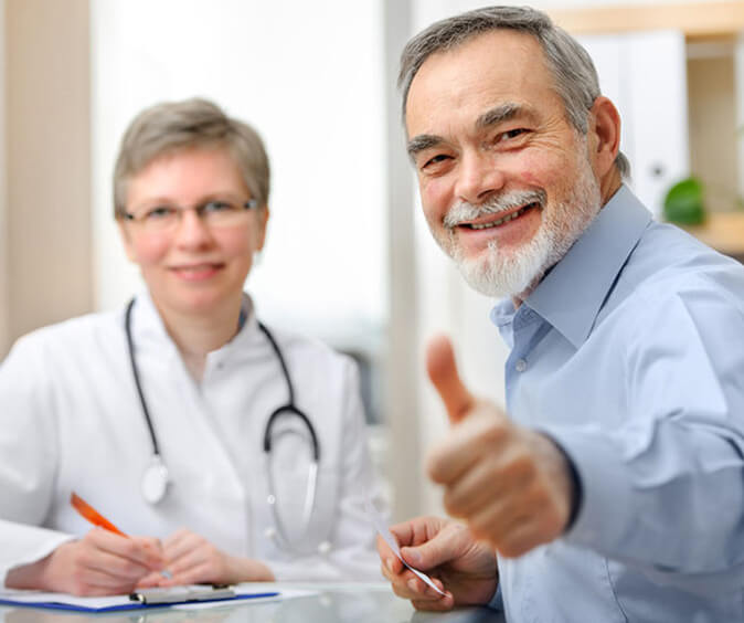 a patient giving thumbs up with doctor in the background